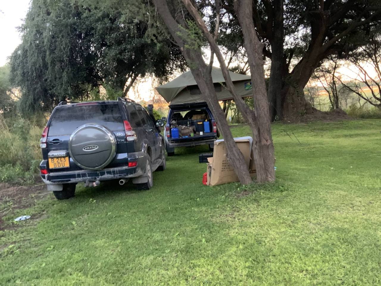 An SUV with a rooftop tent set up at a shaded campsite