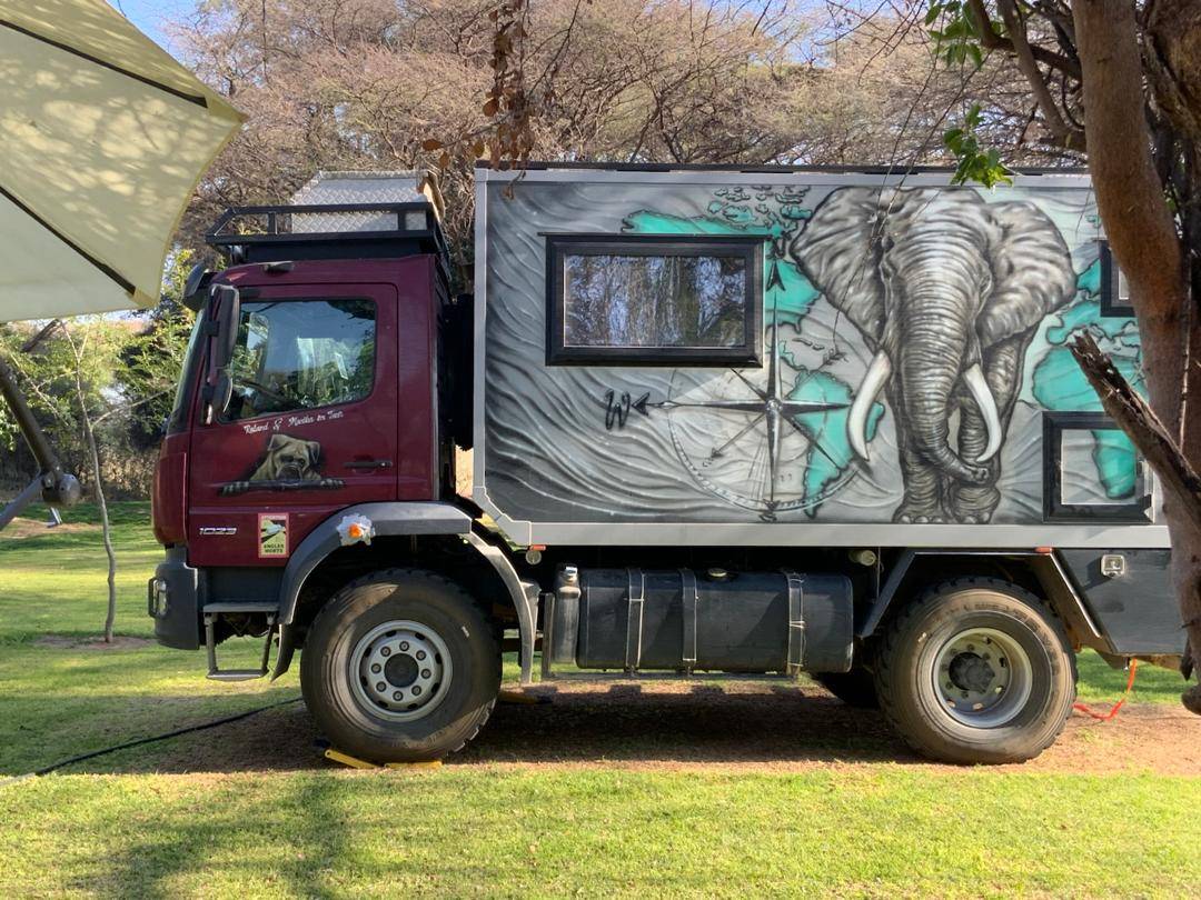 An overland expedition truck with elephant artwork parked on the grass