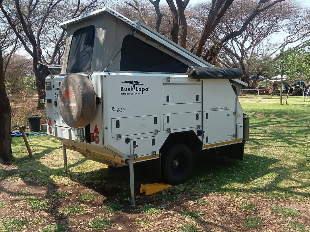 An off-road camping trailer set up on the grass